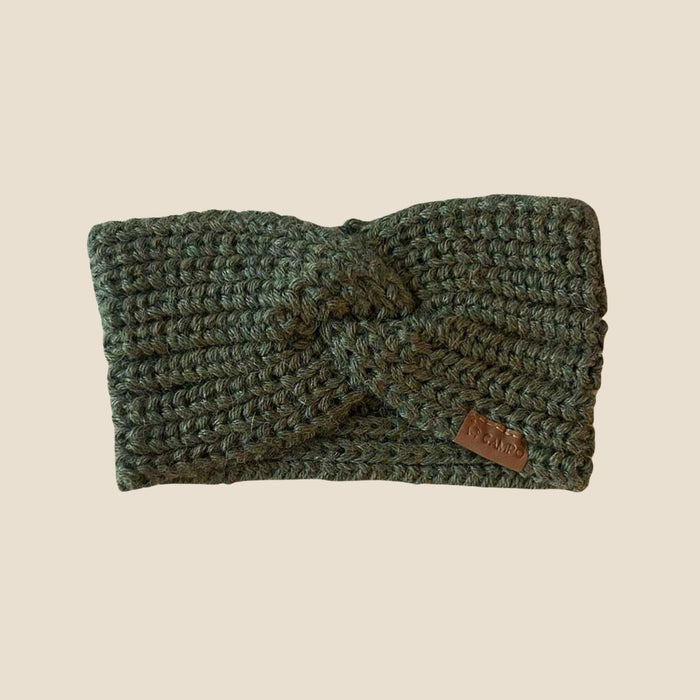 Olive knitted headband with a brown label on a beige background