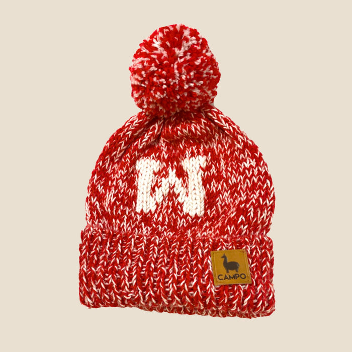 Red and white knitted beanie with pom-pom on a beige background